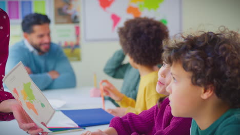 Grupo-De-Estudiantes-Multiculturales-Levantando-Las-Manos-Para-Responder-Preguntas-En-La-Lección-De-Geografía-En-El-Aula