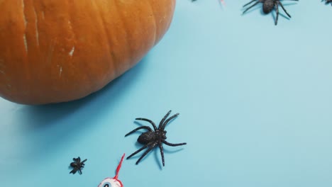 Close-up-view-of-pumpkin-and-halloween-toys-against-blue-background