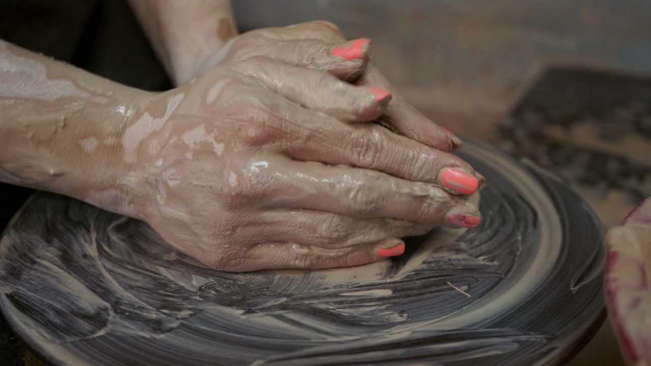 una mujer alfarera hace platos de arcilla. una mujer hace una jarra en la rueda de un alfarero