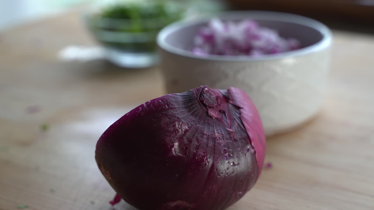 Half of a red onion being dropped on the cutting board special ingredients to cook a meal two cans of beans rice plantain avocado red onion and cilantro