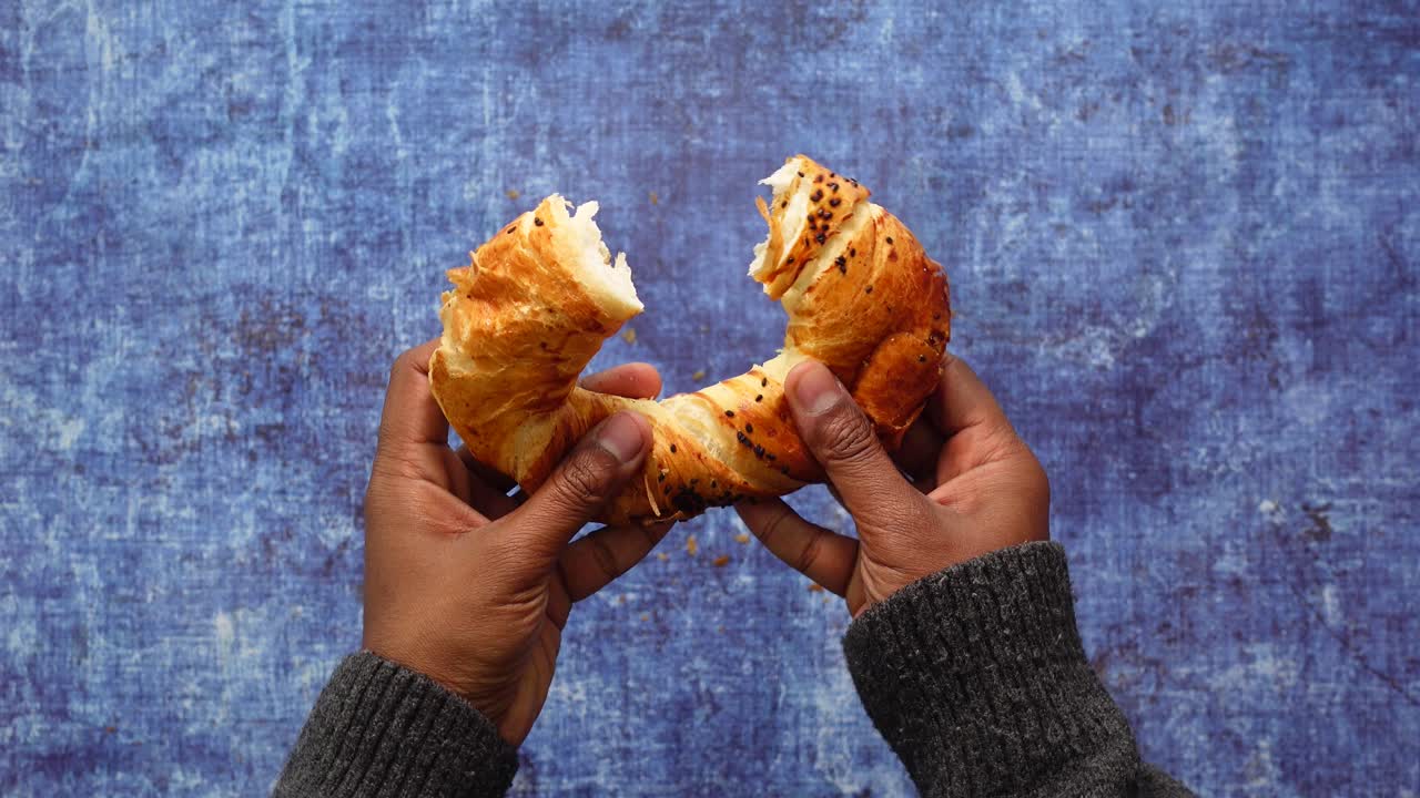 Hands Holding a Broken Croissant