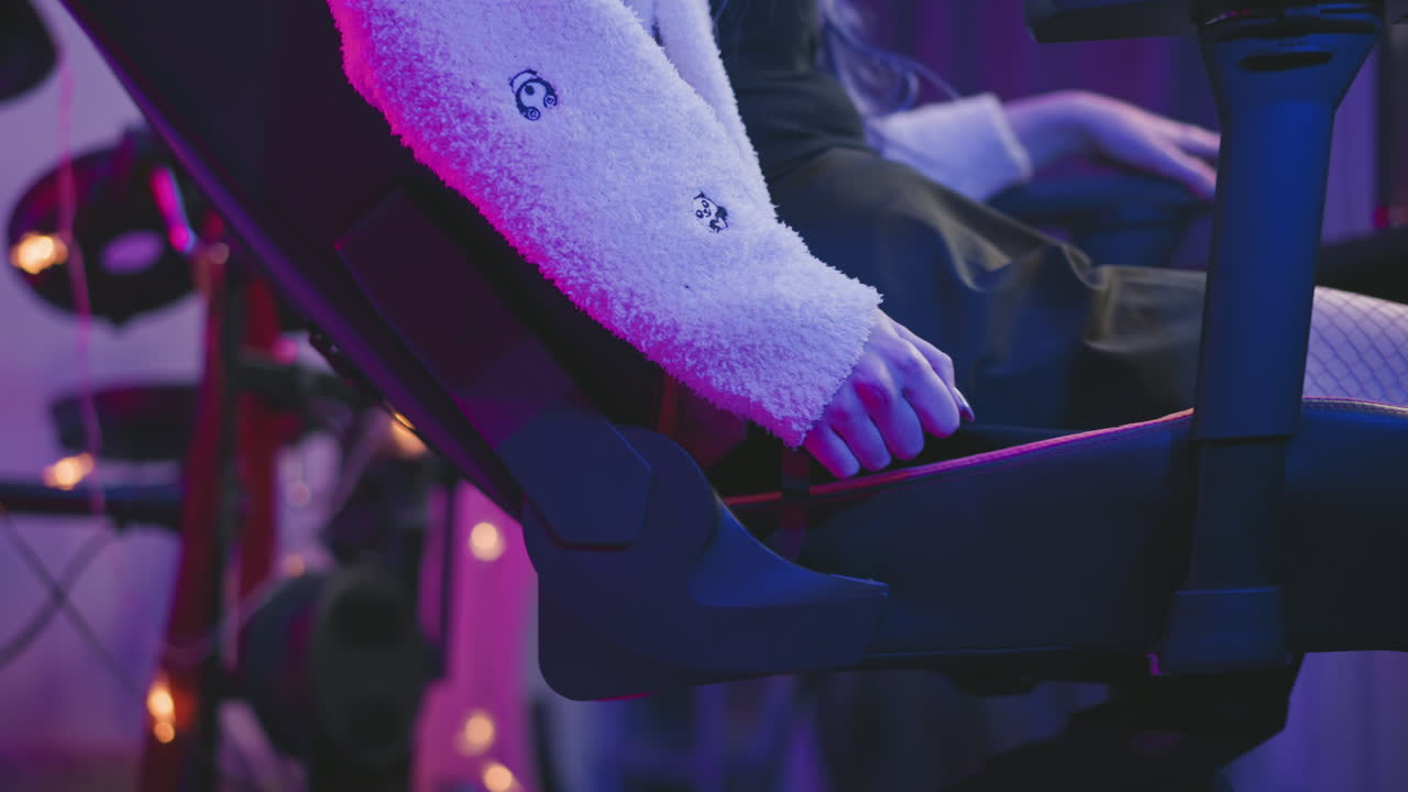 Side view of woman adjusting reclining gaming chair while leaning back in relaxed posture, hand on chair lever, dressed in fluffy sweater, with electronic drum set in background