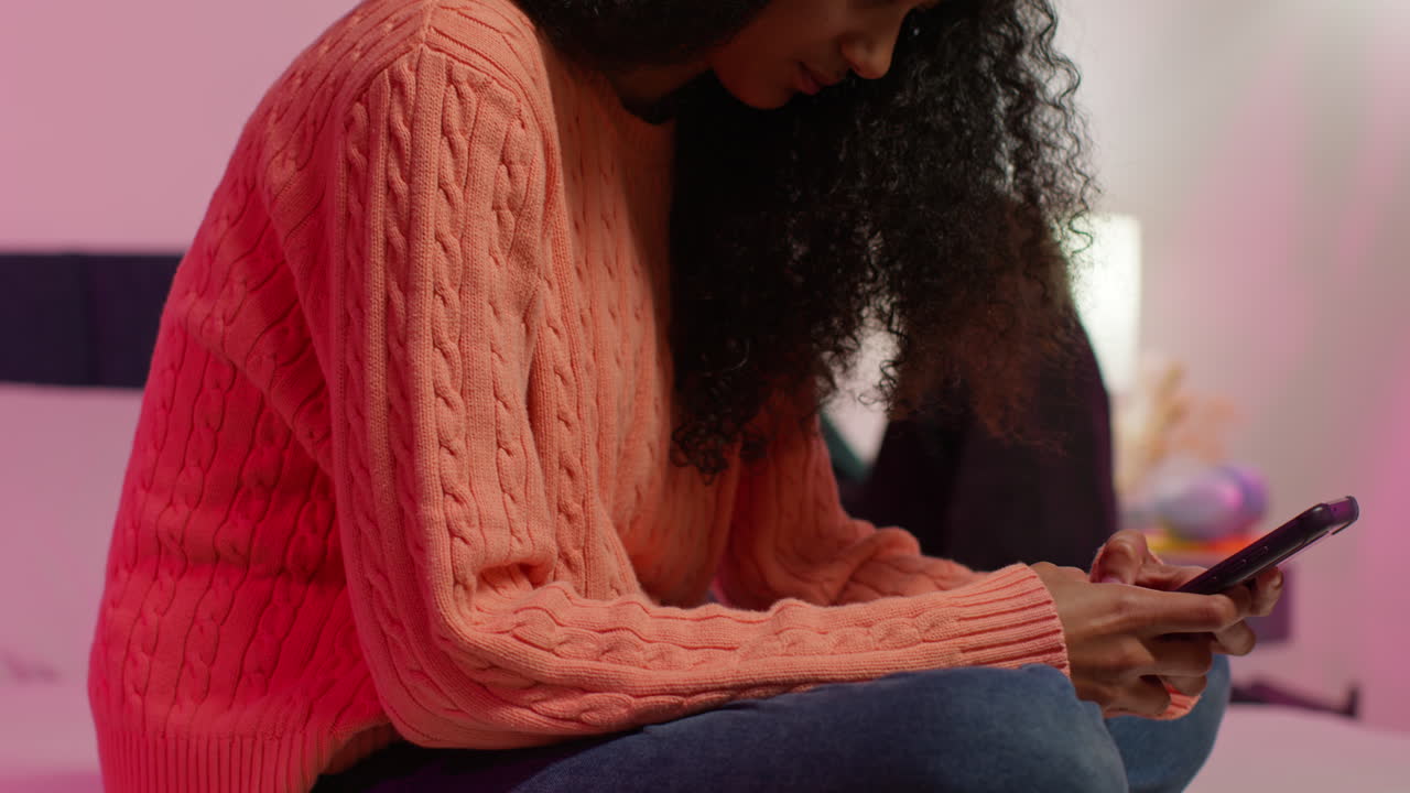 una adolescente usando un teléfono inteligente en el dormitorio