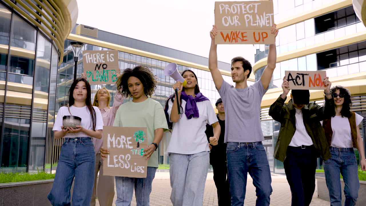 grupo de personas en una protesta usando megáfonos y sosteniendo pancartas 1