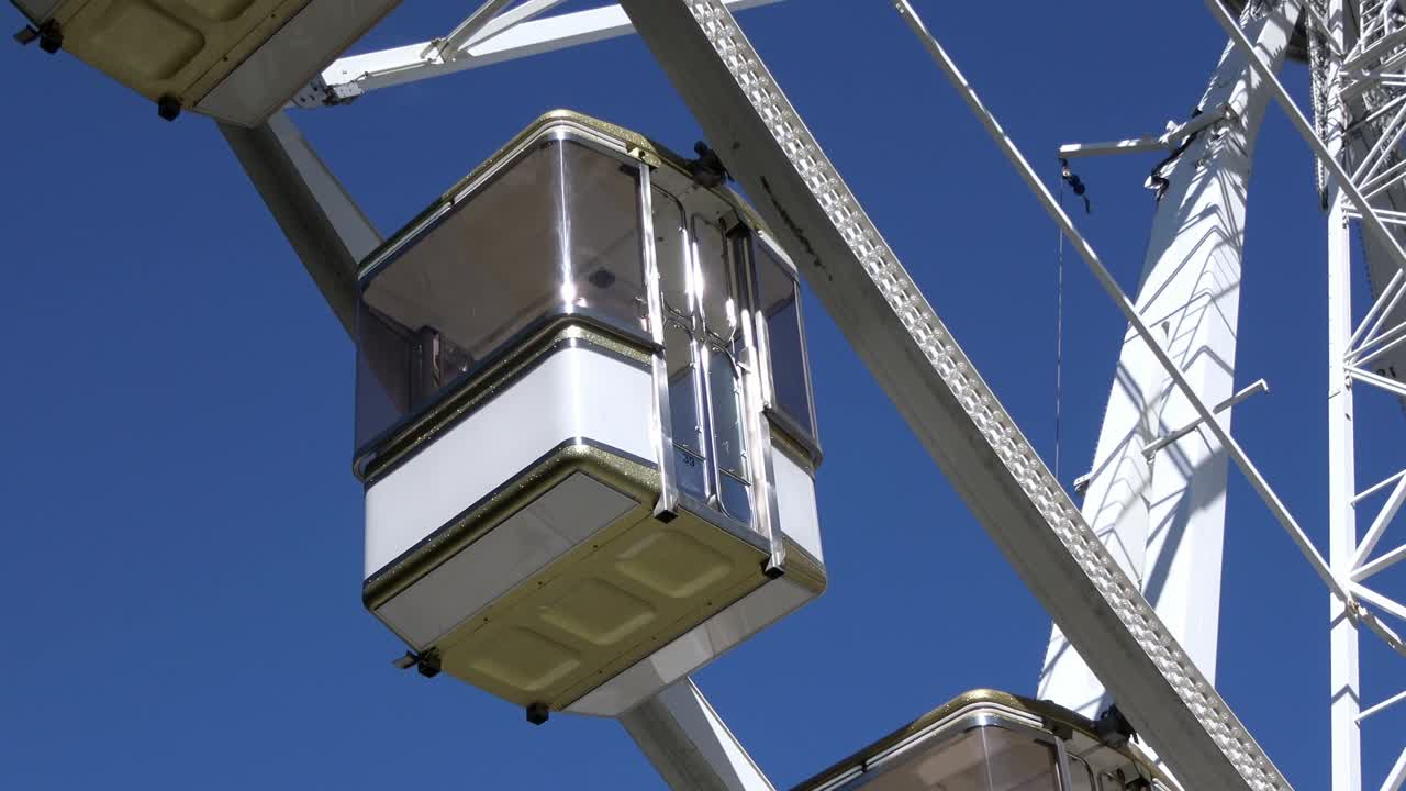 4K. Cabins of a ferris wheel that is standing, passenger cars are hanging