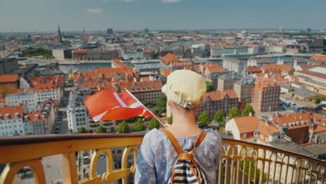 a tourist with a backpack and the flag of denmark rises up the famous spiral staircase of the church