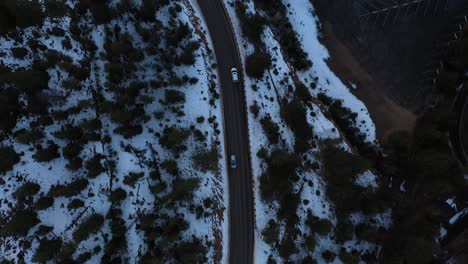 Conducción-De-Automóviles-En-El-Camino-Del-Bosque-Nevado-De-La-Montaña-Toma-Aérea-De-Ojo-De-Pájaro-4k