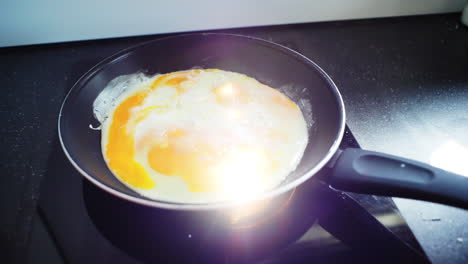 close up capturing golden egg yolks sizzling and transforming while frying on sleek induction cooktop, presenting dynamic lens flare culinary moment