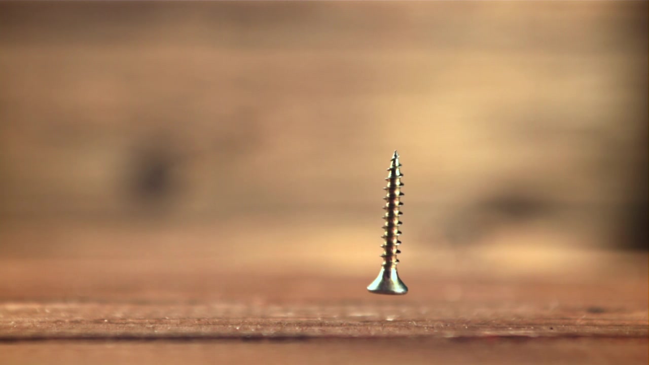 Metal Screw Falling and Spinning in Slow Motion onto Wood