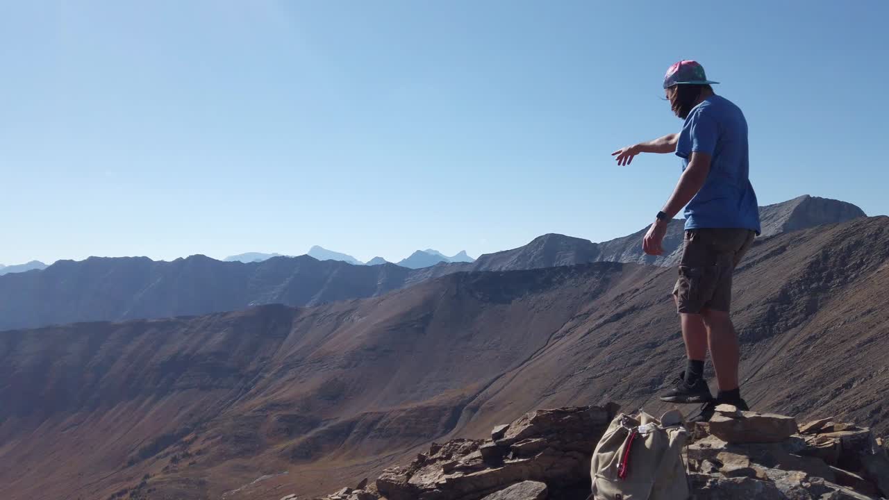 excursionista apuntando al valle en el pico de la montaña pan cámara lenta kananaskis alberta canadá
