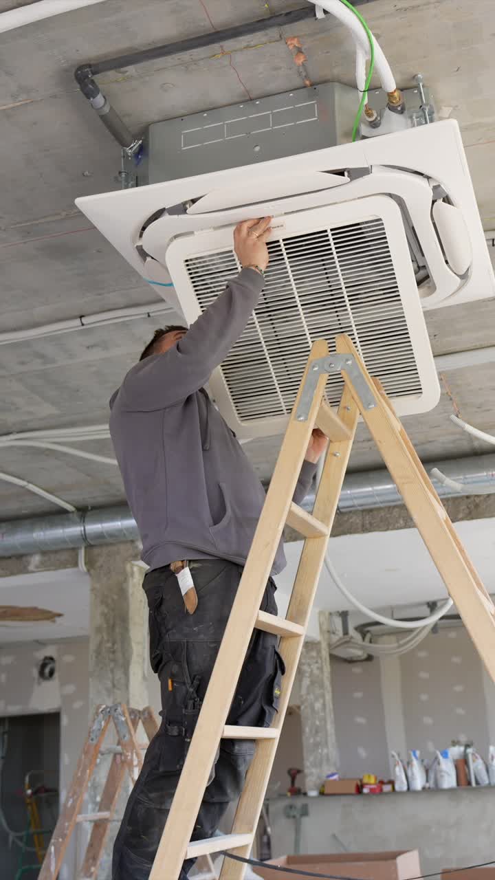 Man Installing Air Conditioning Unit on Ceiling at Construction Site