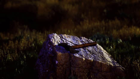 rusty hammer resting on a stone at night in a natural setting