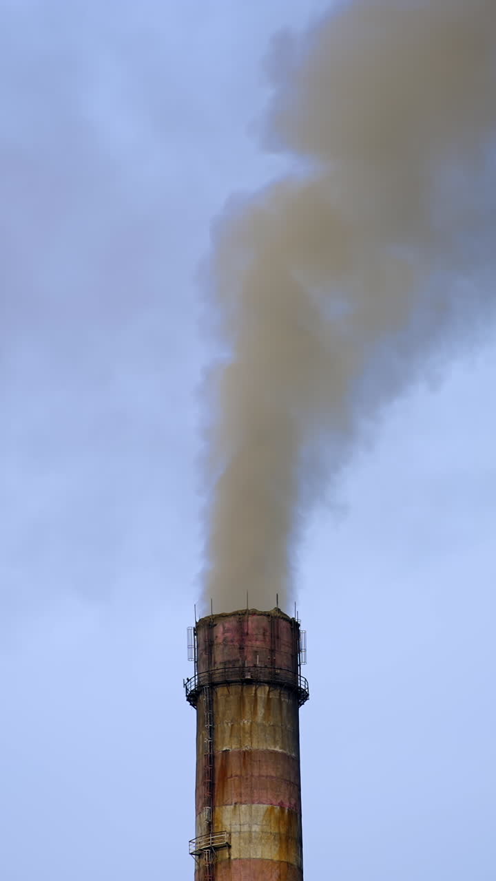 Industrial high pipe with smoke. Pollution of air with dust. Smoking pipe closeup video from a drone. Vertical video