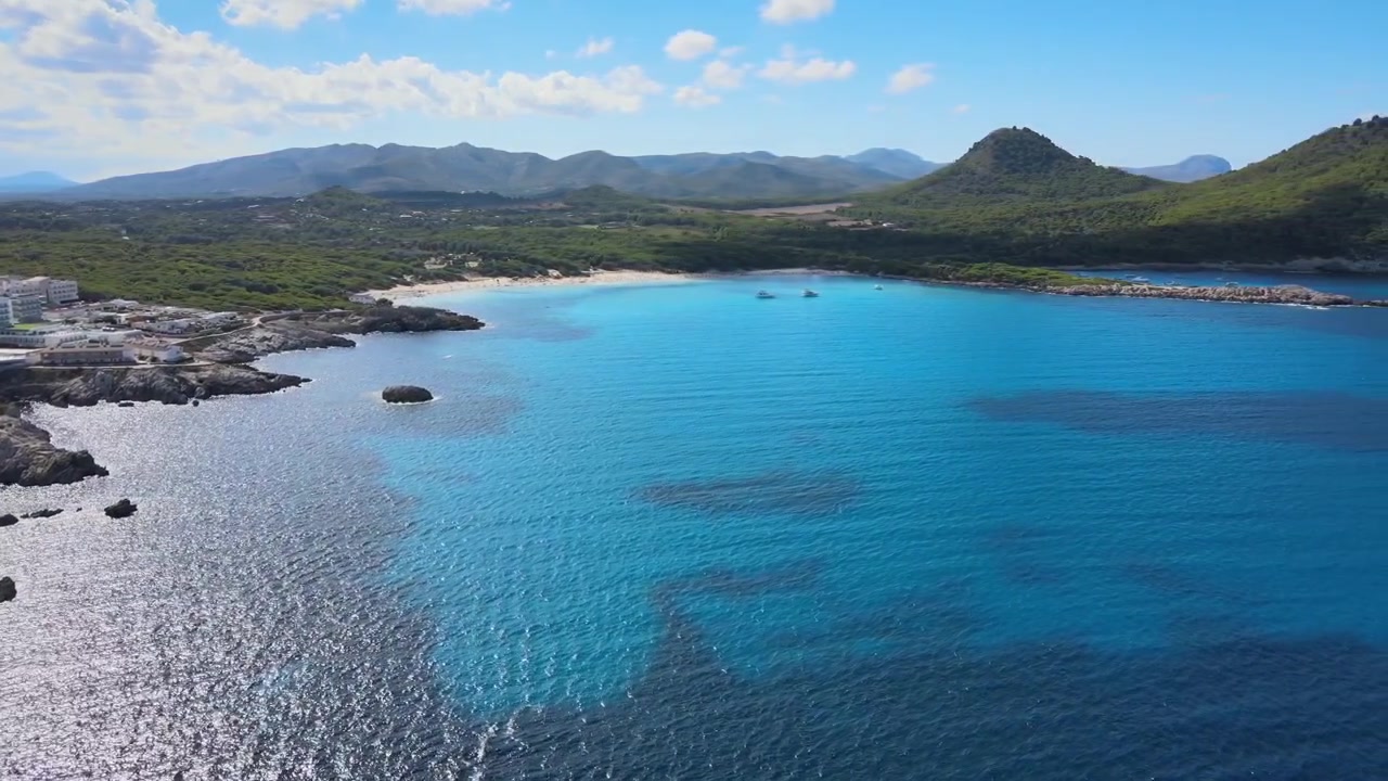 Upplev den hisnande utsikten över Cala Agulla i Cala Rajada, Mallorca. Klart blått vatten, klippiga kuster och frodiga kullar skapar en perfekt tillflyktsort för naturälskare och strandbesökare.