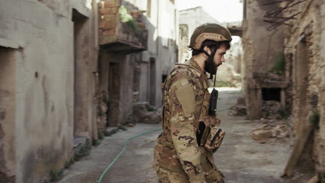 young soldier walks in the destroyed streets of the war torn town