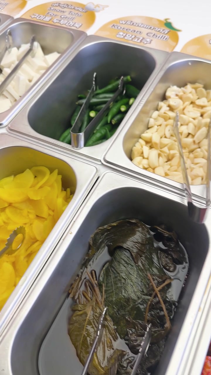 Nærbillede af forskellige koreanske sideretter i metalbeholdere ved en buffet i Bangkok, Thailand