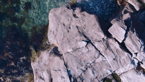 drone flying over cliffy shore with clear water