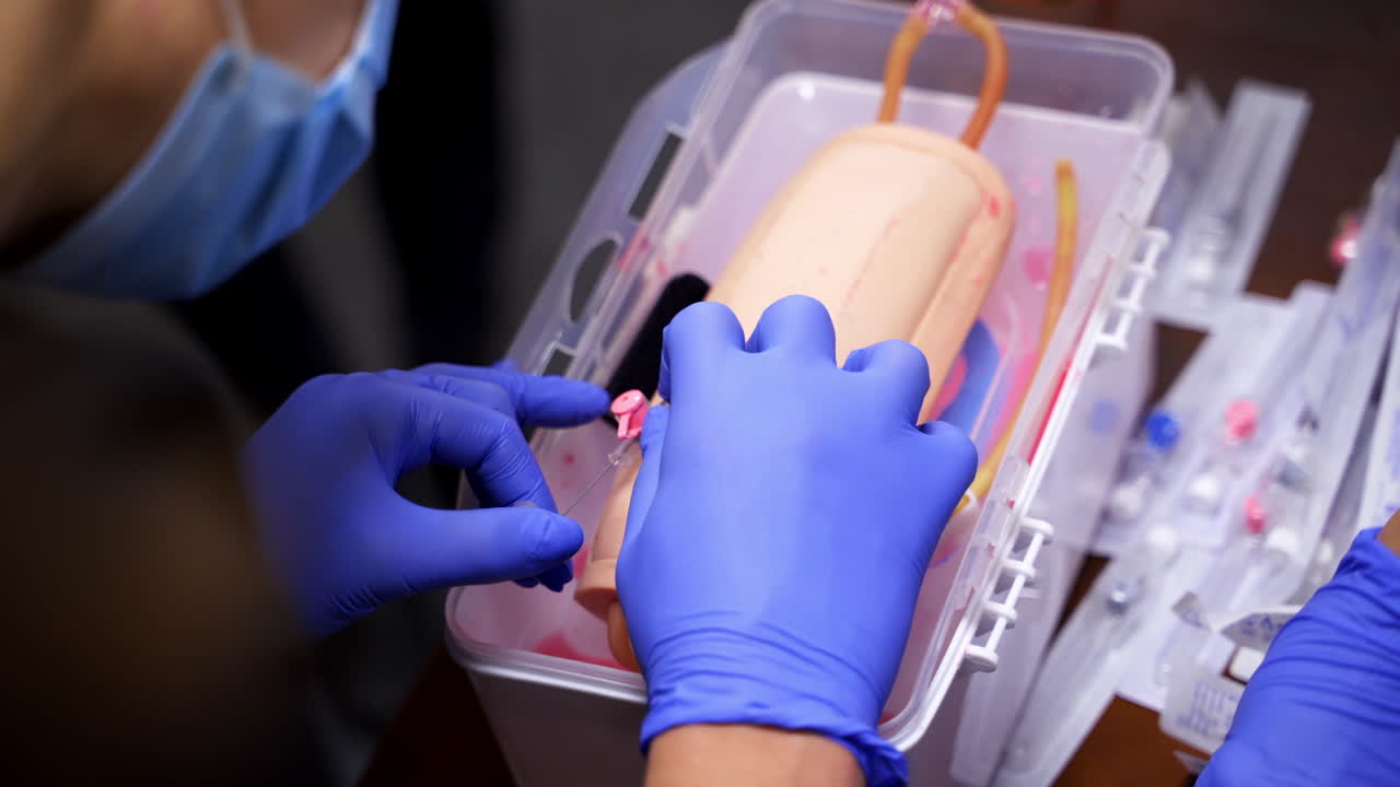 Catheter insertion learning. Students in sterile gloves study to put a catheter on a dummy hand. Medical training. Close-up.