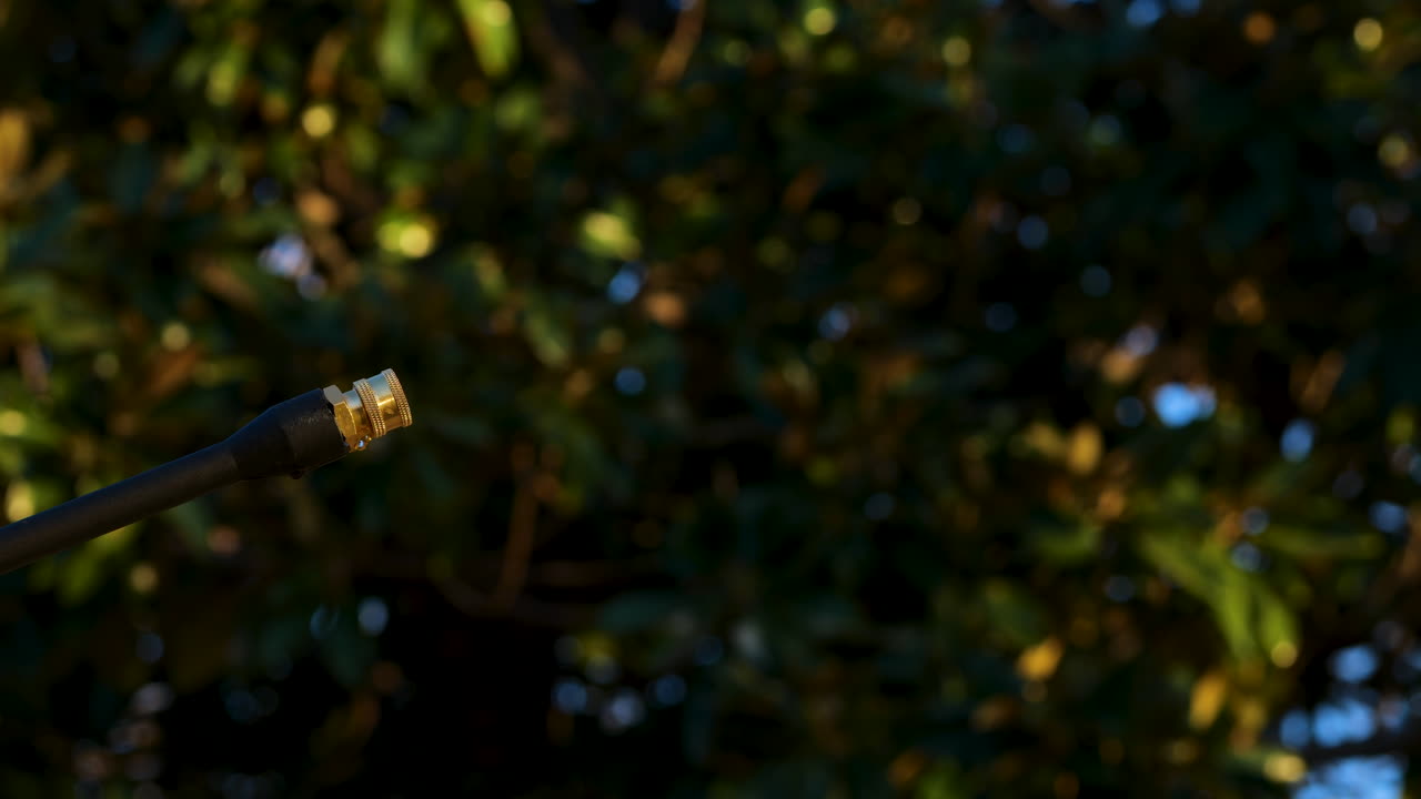 Male caucasian hands remove green nozzle from power washer with trees in the background