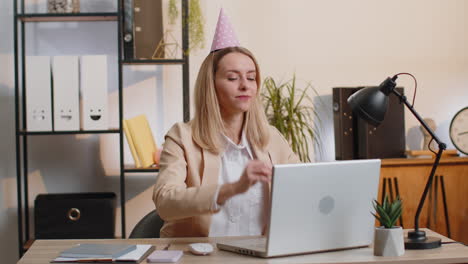 business woman wears sunglasses, festive cap, drinking champagne, celebrating success win at office