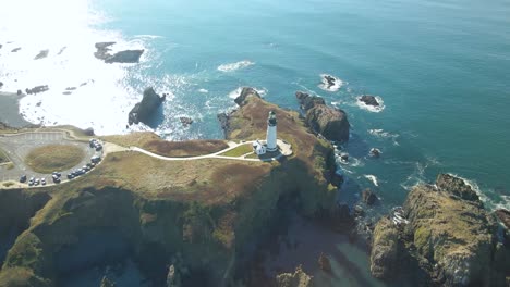 Overhead-aerial-view-of-the-Yaquina-Head-Lighthouse-surrounded-by-blue-water-in-Newport,-Oregon
