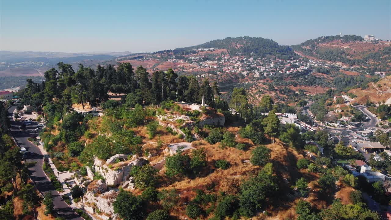 Aerial View of a Hilly Landscape with a Village and Greenery Under a Clear Sky