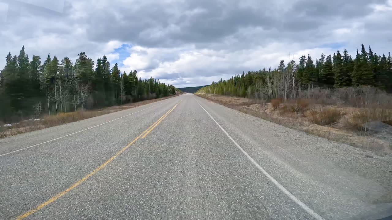 POV, double time - driving on Highway 1 through a taiga forest in western Yukon Territory on in the early spring; concepts Alaska Highway, travel, wilderness and adventure