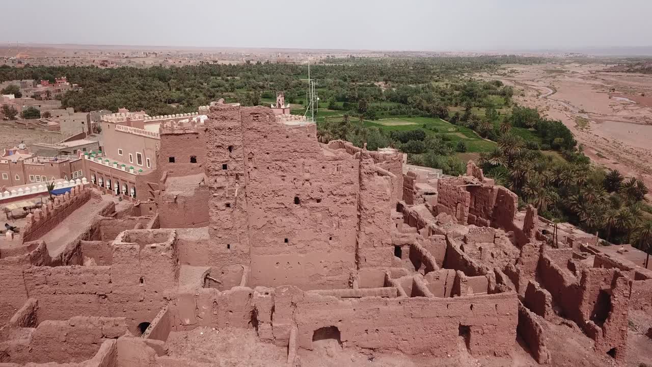 Close-up aerial shot of crumbling red clay walls in a historic Kasbah ruin in Ouarzazate. The detailed texture highlights the decay of traditional earthen architecture in Morocco