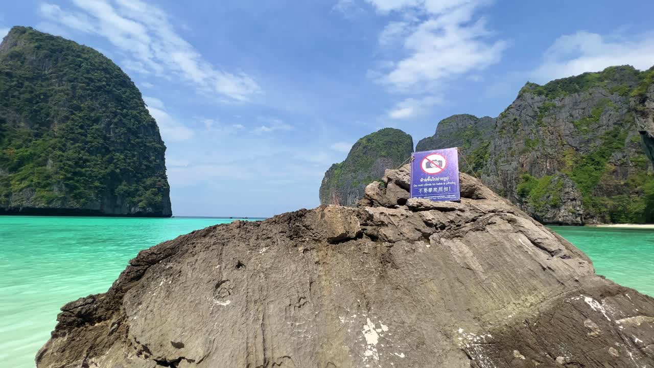 Cartello 'Vietato fotografare' nella Baia di Maya nel Parco Nazionale delle Isole Phi Phi, con le sue onde, la spiaggia di sabbia e le splendide acque cristalline, una popolare destinazione turistica a Krabi, nel sud della Thailandia.