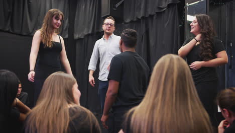 teacher with drama students at performing arts school in studio improvisation class