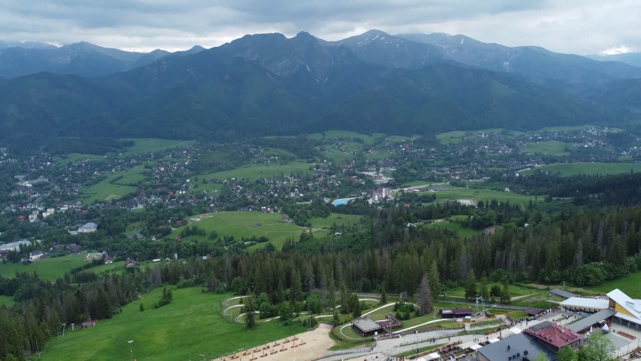 Widok na dolinę z Gubałówki - przelot krajobrazowy nad ośnieżonymi polskimi Tatrami, polami uprawnymi, lasami i legendarnym szczytem Giewont w pobliżu Zakopanego, Polska - 4K 30FPS Płynne panoramowanie w prawo.