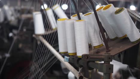 close-up view of thread spools on textile machinery in a factory.