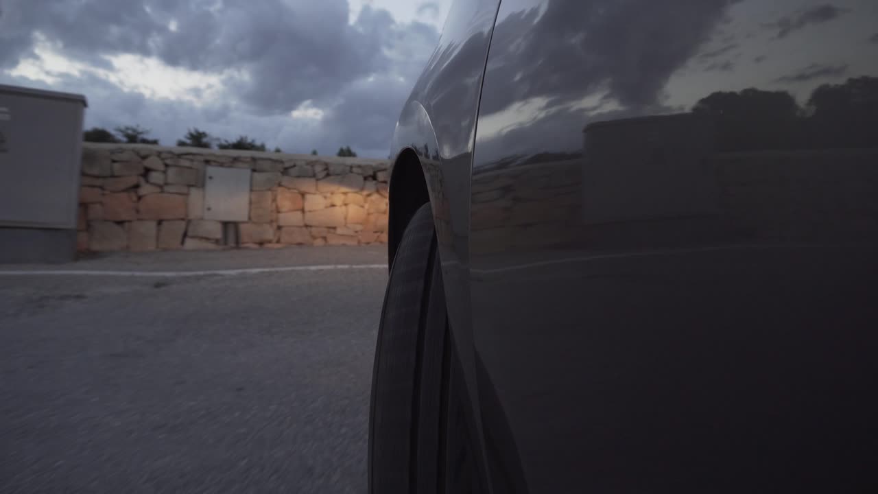 Um carro dirigindo lentamente pela estrada antes do pôr do sol.