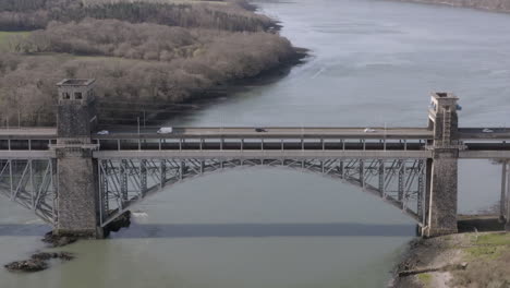 Aerial-view-of-the-Pont-Britannia-railroad-bridge,-flying-left-to-right-around-the-bridge-while-zoomin-out-on,-Anglesey,-North-Wales,-UK