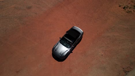toma cinematográfica aérea de un coche cabriolet convertible posicionado en el corazón del desierto dentro del parque nacional del valle de la muerte