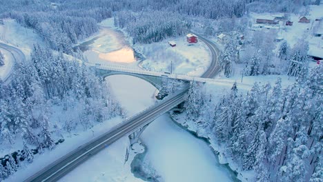 Schöne-Aussicht-Auf-Straße-Und-Eisenbahn,-Die-Sich-Im-Winter-über-Den-Fluss-In-Den-Bergen-Kreuzen