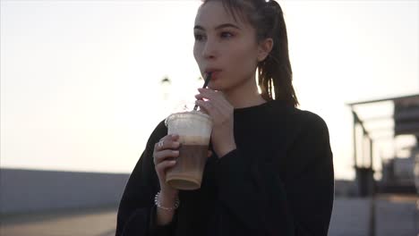 young woman enjoying iced coffee outdoors