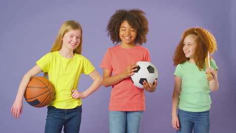 fotografía de estudio de niños con equipos deportivos para fútbol, baloncesto y béisbol sobre un fondo púrpura