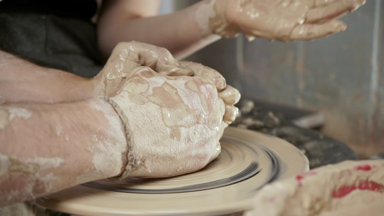 un alfarero enseña a una mujer a hacer platos de arcilla. un hombre toma las manos de una mujer