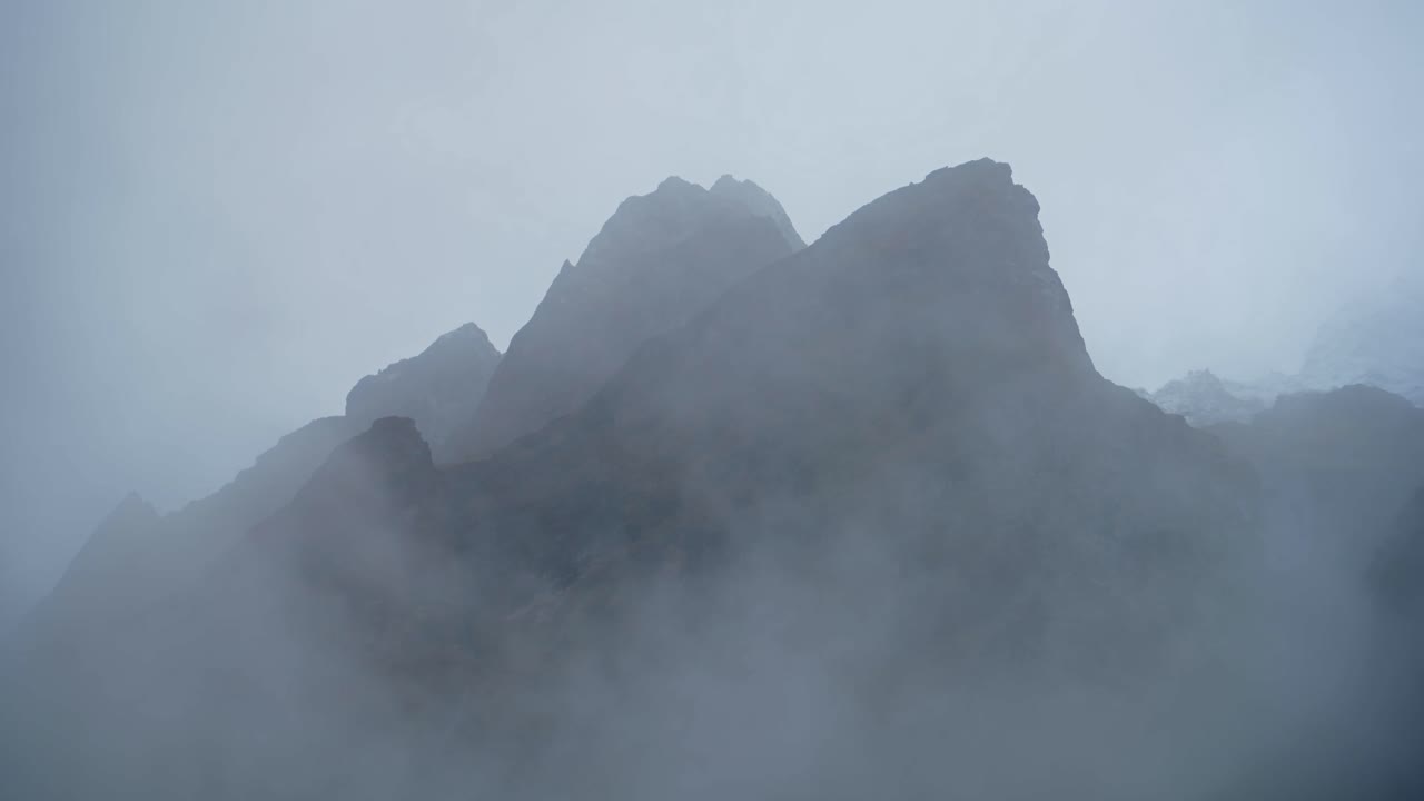 Jagged Rugged Mountains Background with Copy Space, Minimalist Blue Dramatic Mountain Top Background with Copyspace, Moody Atmospheric Scene with Misty Mist and Clouds