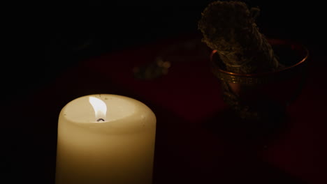 pagan altar in candlelight as sacred ritual sage stick rests in offering bowl