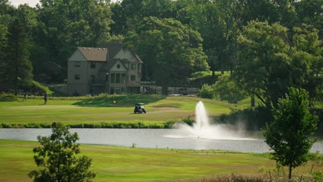 golf cart parked next to a green with a foreground fountain inside a pond