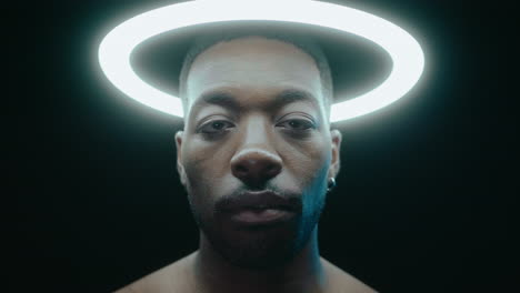 black man posing under ring light in dark studio