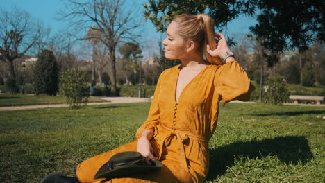 stylish young woman sitting in the grass outdoors.