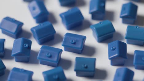 home buying concept with hand clearing away group of blue plastic models of houses revolving on white background