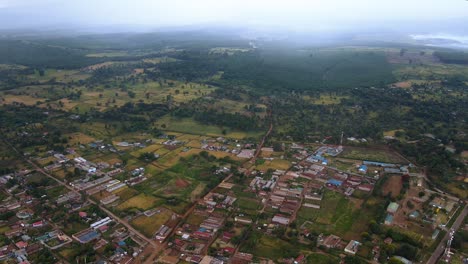 Aerial-view-of-rain-moving-towards-a-rural-town-in-Kenya---descending-drone-shot