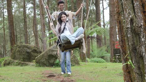 indonesian friends playing on a swing in forest during outdoor travel adventure