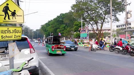 green tuk-tuk driving past a crowded street