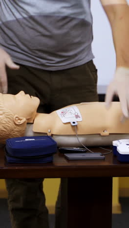 trainer teaching medical skills on a mannequin. instructor showing practical methods for giving first aid on a dummy. healthcare and medical concept. vertical video