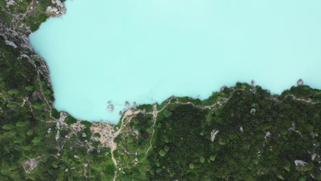 una vista de pájaro del lago turquesa en los dolomitas italianos